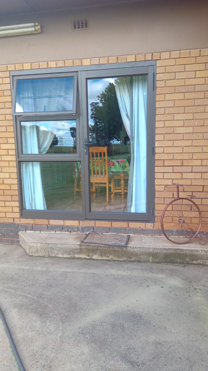 charcoal aluminium hinged door and top-light on face brick exterior