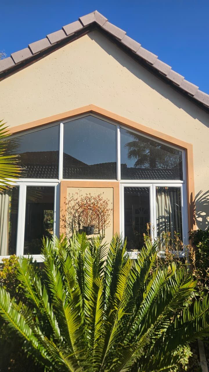 gable-end feature window above white aluminium windows on a tiled-roof home
