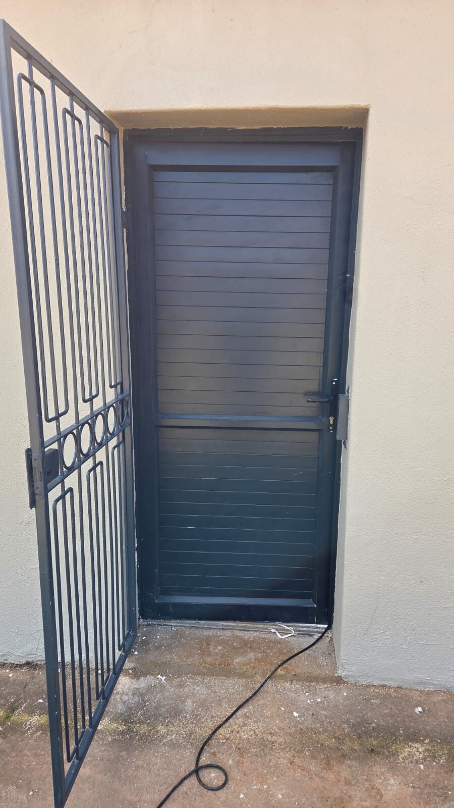 black aluminium louvre security door fitted into a plastered opening