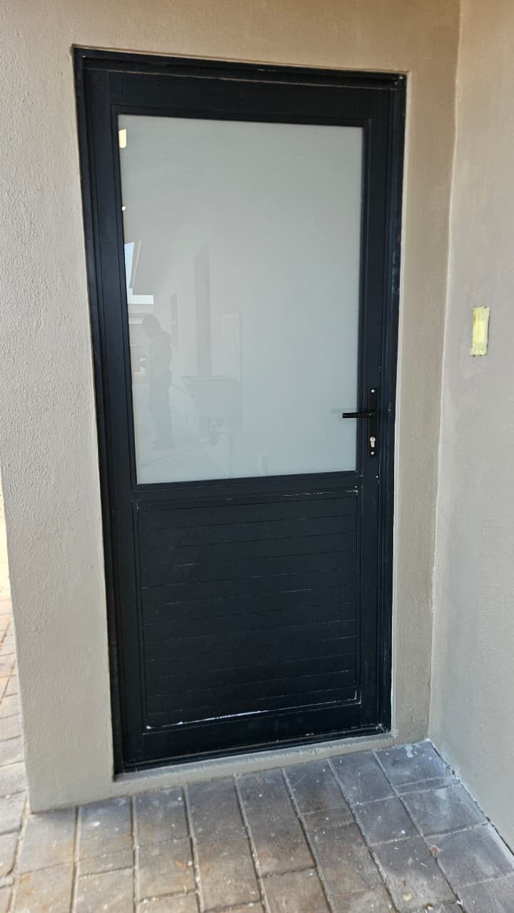 black aluminium single door with obscure glass on a plastered wall