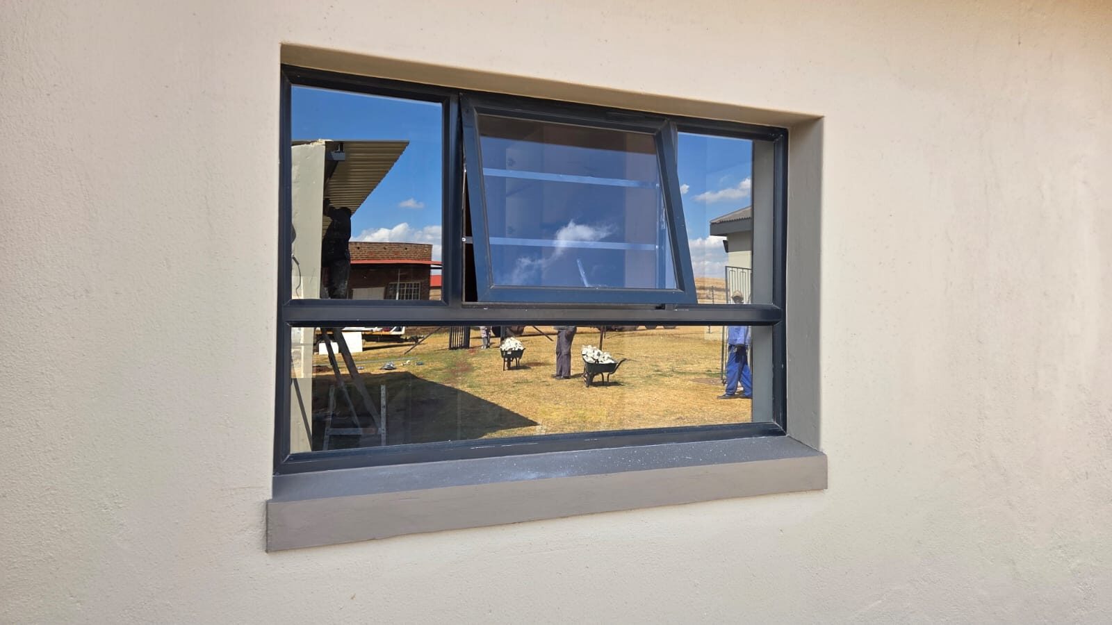 charcoal aluminium awning window with a bevelled sill on a plastered wall