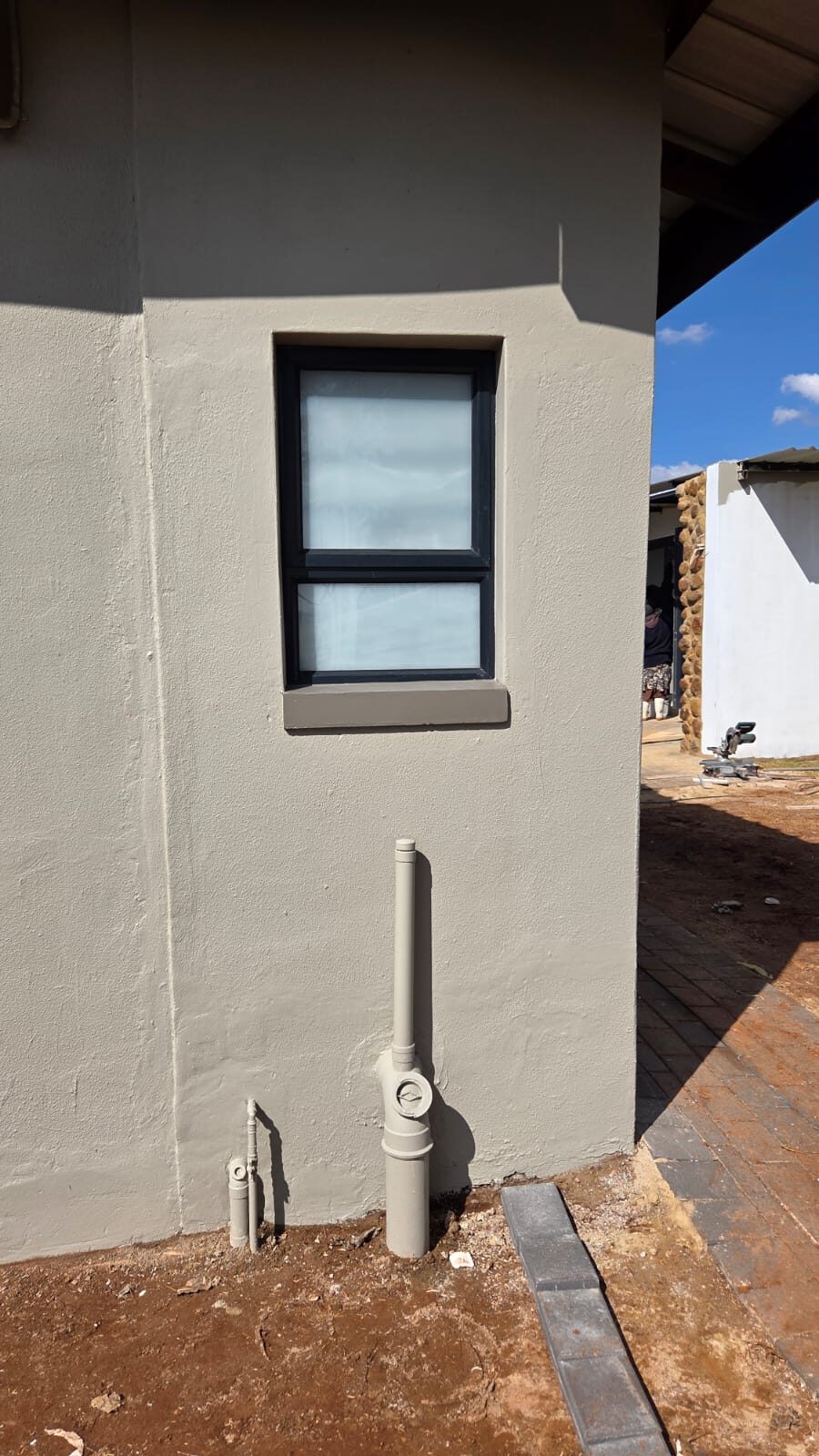 compact charcoal aluminium window on a grey plastered corner wall