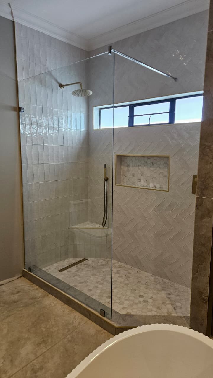 frameless glass shower screen beside a charcoal aluminium clerestory window